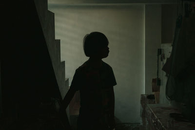 Silhouette boy standing by stairs at home