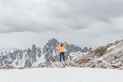 Woman standing on snow covered mountain against sky