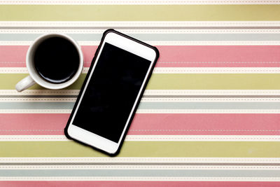 High angle view of coffee by mobile phone on table