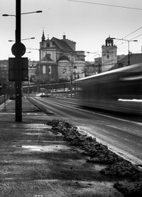 Railroad tracks by street in city against sky