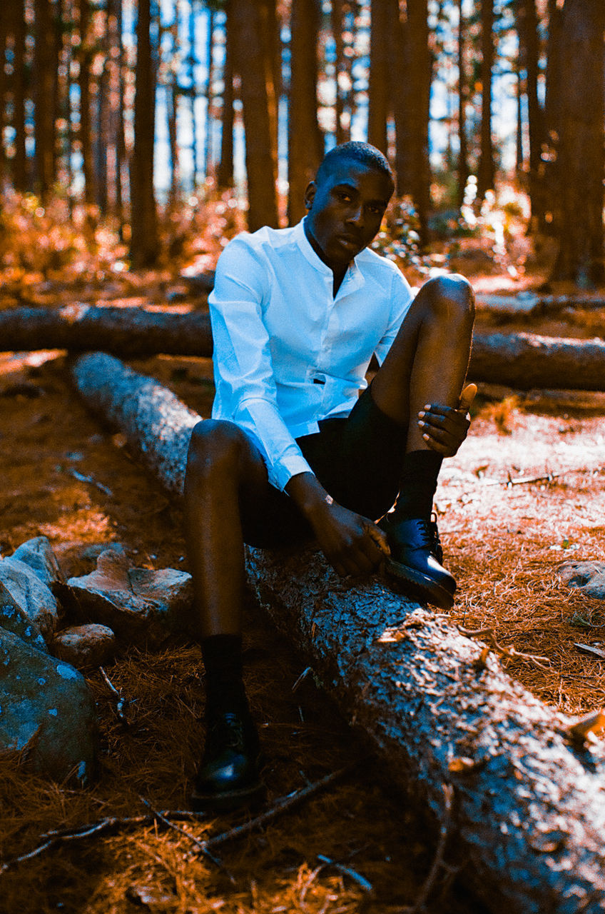 YOUNG MAN SITTING ON ROCK IN THE FOREST