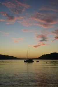 Silhouette sailboat in sea against sky during sunset