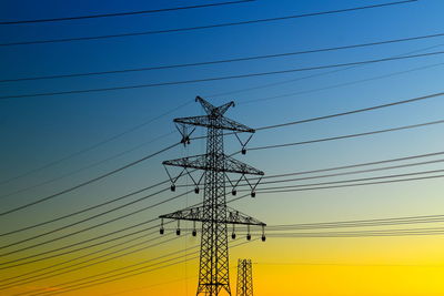 Low angle view of silhouette electricity pylon against sky during sunset