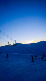 People skiing on snow covered mountain against sky