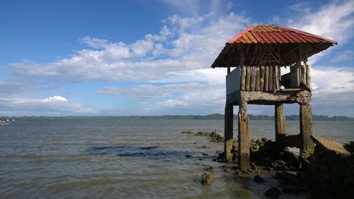 Lifeguard hut in sea against sky