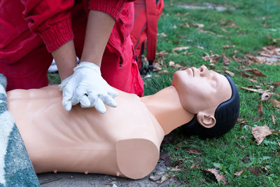 Midsection of paramedic performing cpr on mannequin