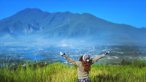 Rear view of woman standing on field against sky