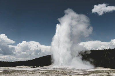 Water spraying from geyser against sky