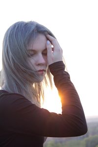 Close-up of woman looking down against sky during sunset