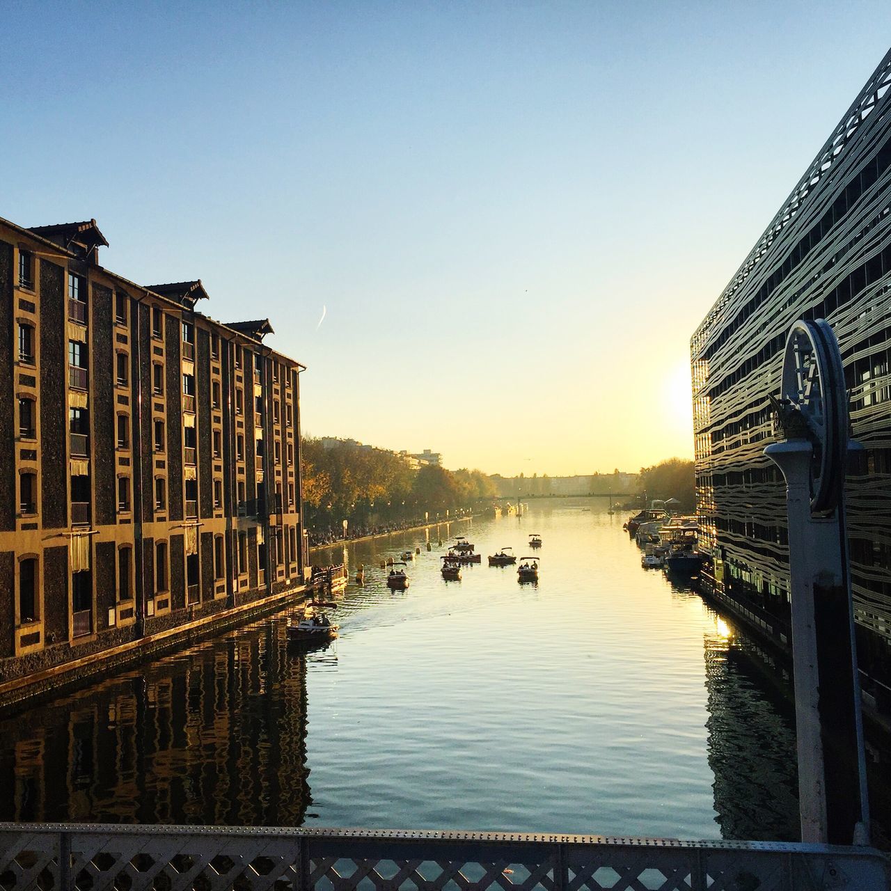 clear sky, architecture, built structure, building exterior, water, copy space, city, river, sunset, canal, transportation, reflection, blue, bridge - man made structure, outdoors, building, no people, travel destinations, waterfront, sunlight