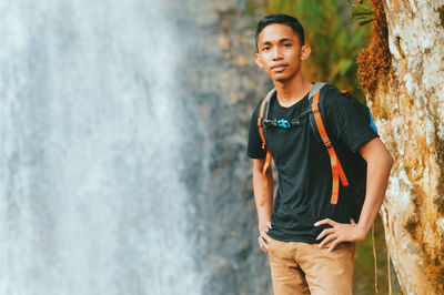 Portrait of young man standing against tree