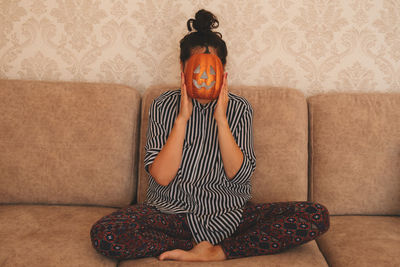 Midsection of person sitting on sofa against wall