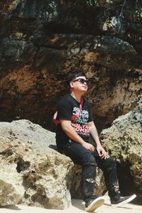 Full length of young man sitting on rock