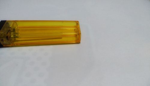 High angle view of yellow glass on table against white background