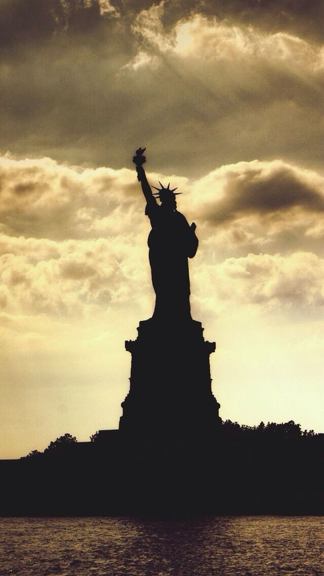 statue, human representation, sculpture, art and craft, art, creativity, sky, silhouette, cloud - sky, water, statue of liberty, sunset, famous place, travel destinations, waterfront, travel, tourism, animal representation