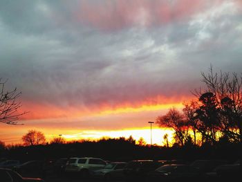 Silhouette trees against dramatic sky during sunset