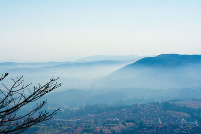 Aerial view of townscape by mountains against sky