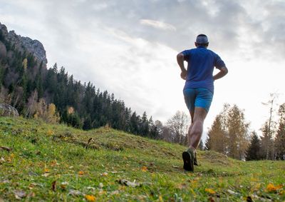 Rear view of man running on grass