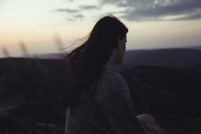 Woman standing on landscape at sunset