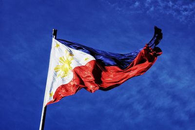 Low angle view of philippines flag waving against blue sky