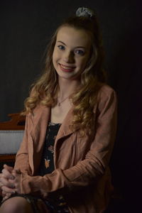 Portrait of smiling young woman against black background