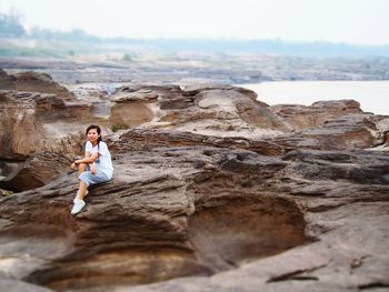 Young woman sitting on rock formation