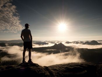 Man at the top of a mountain looking the misty landscape around. feel free