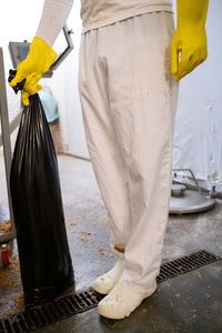 Low section of man holding plastic bag