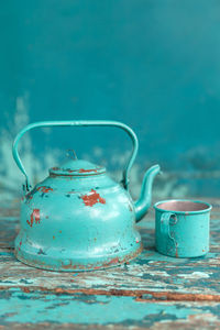 Close-up old kettle and cup on weathered table