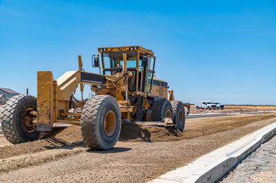 Yellow excavator, road repair. close-up. blue sky background.