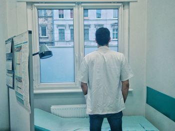 Rear view of doctor standing against window in hospital