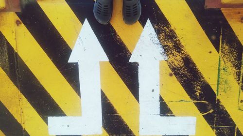 High angle view of yellow arrow sign on road