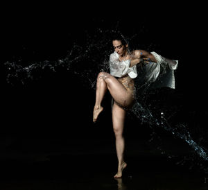 Portrait of woman dancing against black background