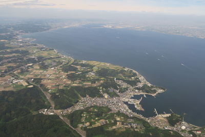 Aerial view of city by sea against sky