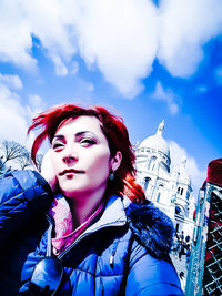 Low angle portrait of woman against blue sky