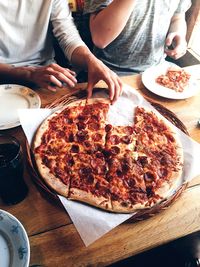 Midsection of friends having pizza in restaurant