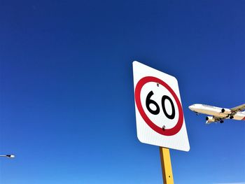 Low angle view of road sign against blue sky