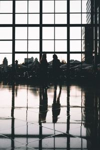 Silhouette people standing at airport against sky