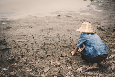 Rear view of girl kneeling on drought field