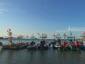 Boats moored at harbor against blue sky