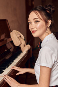 Asian high school student sitting at the piano