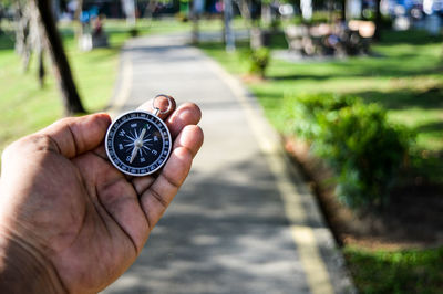 Cropped hand of person holding navigational compass at park