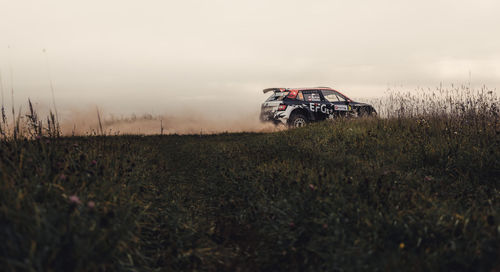 Abandoned car on field against sky