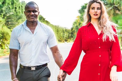 Multi-ethnic couple holding hands while walking on road
