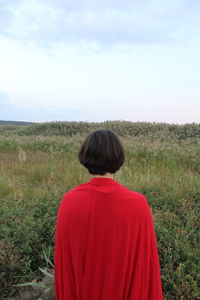 Rear view of woman standing on grassy field against sky