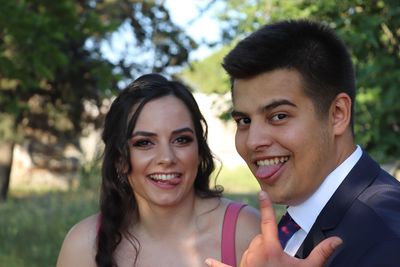 Portrait of smiling young couple sticking out tongue while standing outdoors