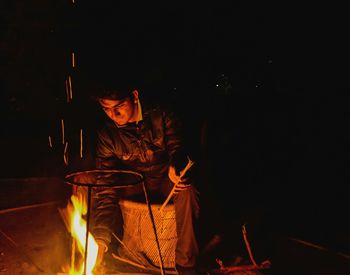 Man sitting near bonfire at night during winter