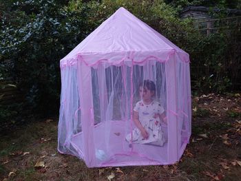 Young girl in pink fairy tent in back garden 