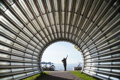 Rear view of man standing in front of tunnel with hand up