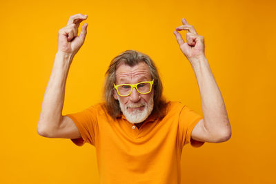 Portrait of senior man against yellow background